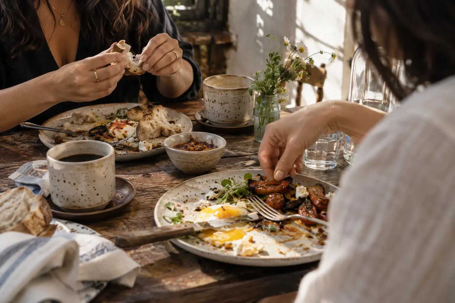 Dos amigas comparten desayuno y café en una mesa de madera